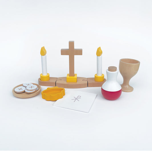 Children's church play set including a buildable altar piece with a cross and candles, a wine cruet, a chalice, a chalice pall, a paten, six hosts, and a baptismal shell.