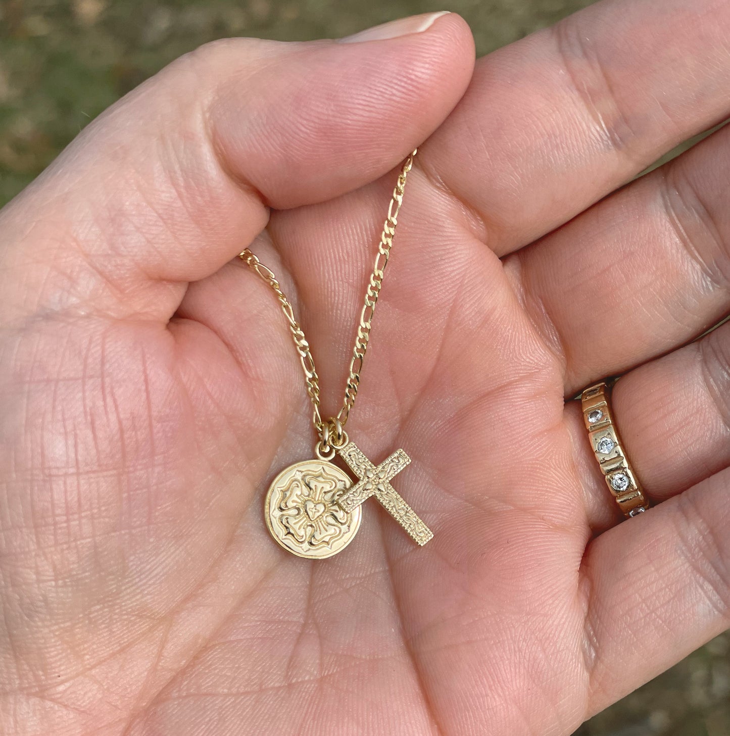 A gold Lutheran necklace with a cross pendant resting in an open hand.