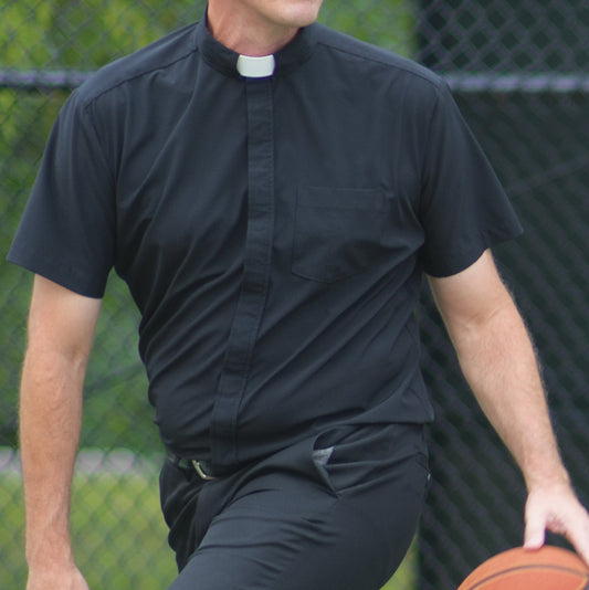 A clergyman wearing a Wicking Vicar black clerical shirt while playing basketball on an outdoor court.